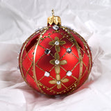 Rund julekule I glass. Malt i rødt, dekorert med gull, hvite perler og blanke glassteiner. Juletrepynt, påskepynt