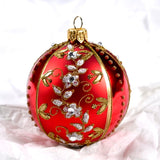 Rød rund julekule i glass med gull- og sølvdekor og blanke glassteiner